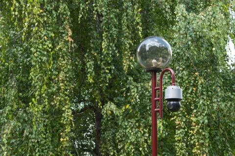 Security camera CCTV mounted on light pole to monitor people in public park Stock Photos