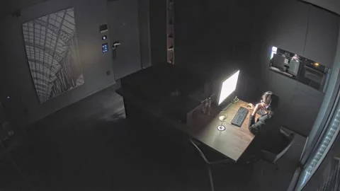 Security Camera Controlling a Woman Working Late at Home Stock Footage