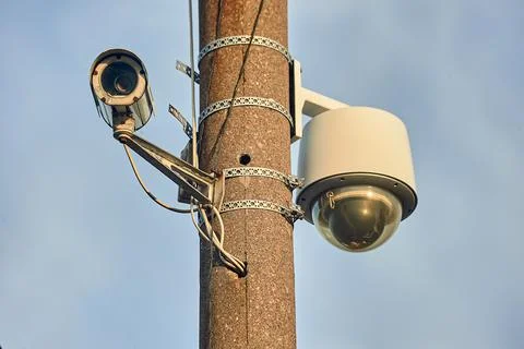A security camera is hanging on a concrete post Stock Photos