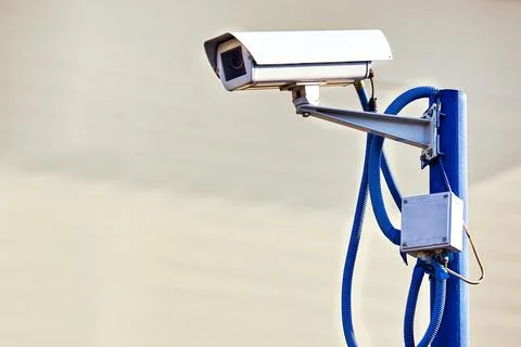 This is a security camera hanging on a pole on a summer day on a gray background Stock Photos