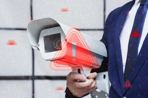 Security camera held by businessman in suit with red warning sign overlay and 库存照片