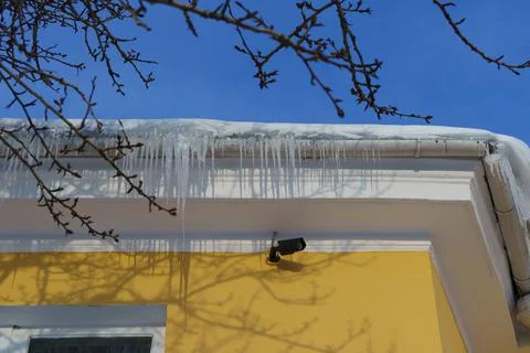 Security camera on house wall next to icicles in winter Stock-Fotos