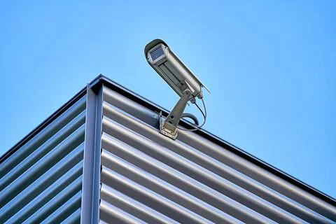 Security camera installed on the building wall in the city against blue sky Foto stock
