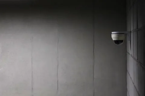 A security camera installed on a concrete wall. Stock Photos