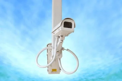 Security camera isolated on blue sky background. Stock Photos