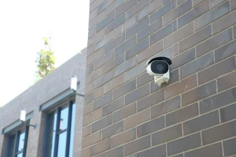 Security camera mounted on a brick wall in a city setting Stock Photos