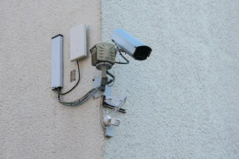 Security camera mounted on a building corner monitoring outdoor area Stock Photos