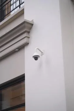 Security camera mounted on building wall in urban setting Stock Photos