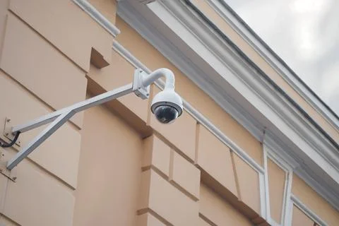 Security camera mounted on a building wall in daylight Stock Photos