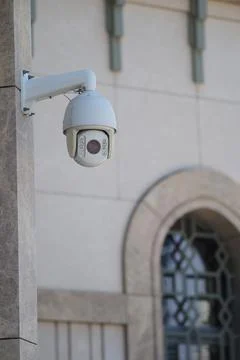 Security camera mounted on building wall in city area Stock Photos