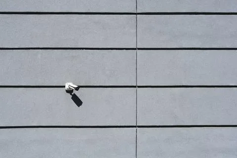 Security camera mounted on a modern grey concrete panel wall Stock Photos