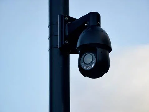 Security camera mounted on a pole against a clear sky Stock Photos