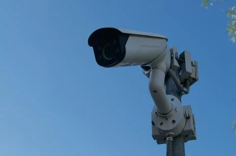 Security camera mounted on a pole against a clear blue sky Stock Photos
