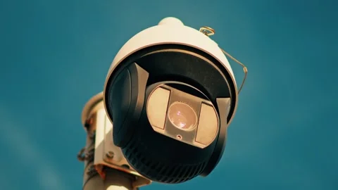 Security camera mounted on pole rotating and surveilling area against blue sk Stock Footage 339640138