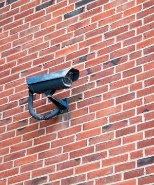 Security camera mounted on a red brick wall providing surveillance and prot.. Stock Photos
