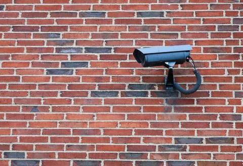 Security camera is mounted on a textured brick wall, ensuring protection an.. Stock Photos