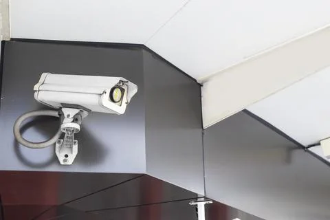 The security camera is mounted on top of a dark-colored wall on the exterio.. Stock Photos