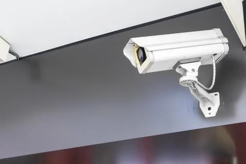The security camera is mounted on top of a dark-colored wall on the exterio.. Stock Photos