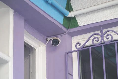 Security camera mounted on wall in bright colored building Stock Photos