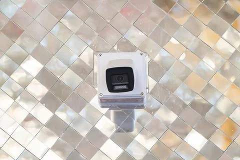Security camera mounted on wall with reflective mosaic background. Device p.. Stock Photos