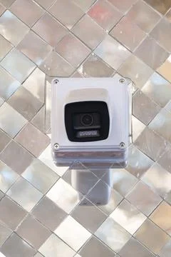 Security camera mounted on wall with reflective mosaic background. Device p.. Photos