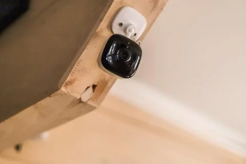 Security camera mounted on wooden beam for indoor home surveillance 库存照片