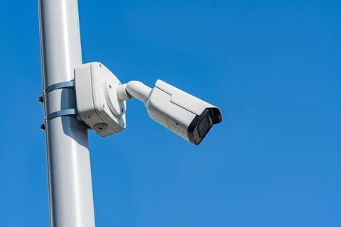 Security camera on a pole in clear blue sky Stock Photos