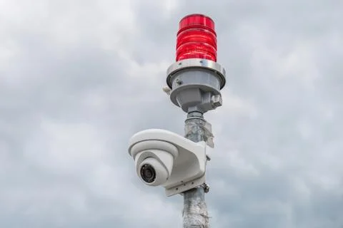 Security camera with red beacon on cloudy sky background Stock Photos