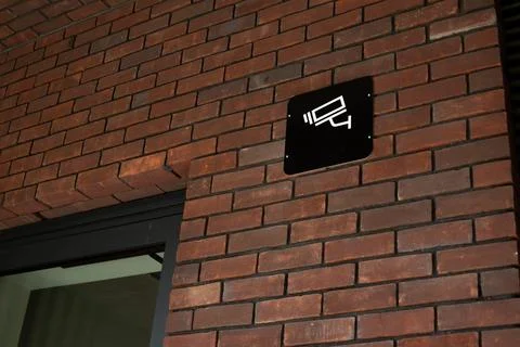 Security camera sign mounted on brick wall, indicating surveillance, common.. Stock Photos
