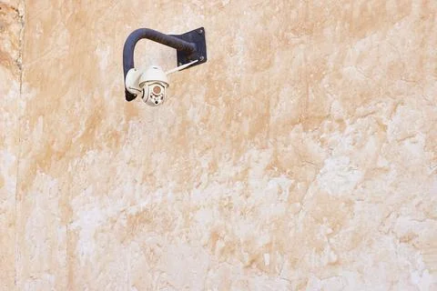 Security Camera On Weathered Orange Wall: Exterior Surveillance In A Rustic Sett Stock Photos