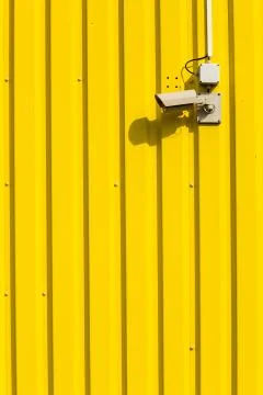 Security camera on a yellow wall Photos