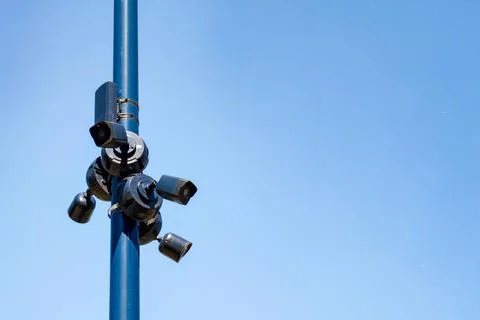 Security cameras mounted on a blue pole against a clear sky showing technology Stock Photos