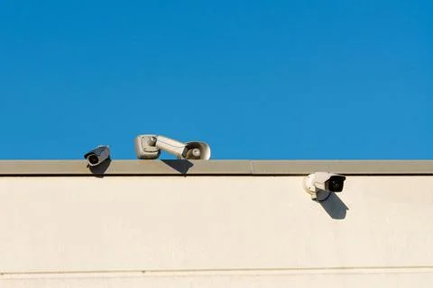 Security cameras mounted on a building under clear blue sky Stock Photos