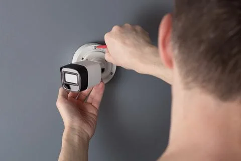 Security cameras in the service engineer hand close up on gray background. Stock Photos