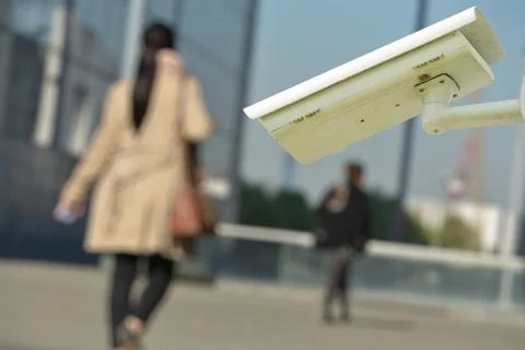 Security CCTV camera or surveillance system with woman on blurry background Stock Photos