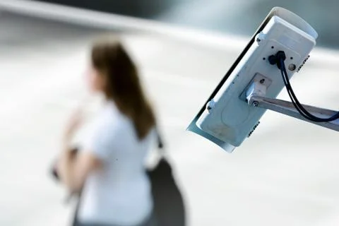 Security CCTV camera or surveillance system with woman on blurry background Stock Photos