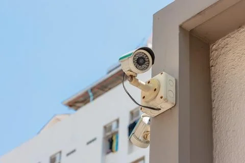 Security CCTV camera or surveillance system in office building on blue sky .. Stock Photos