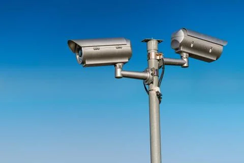 Security CCTV video camera against blue sky. Stock Photos