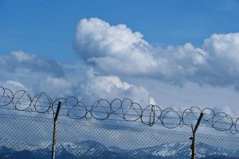 Security concept - barbed wire fence with blue sky and clouds 스톡 사진