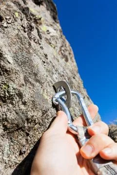 Security concept: climber inserts a quick-draw in anchor on rock wall outdoor Stock Photos