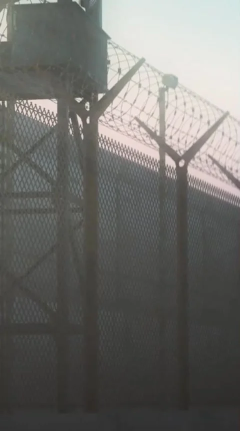 Security Fence with Barbed Wire at Dusk Against Urban Background Stock Footage 306459904
