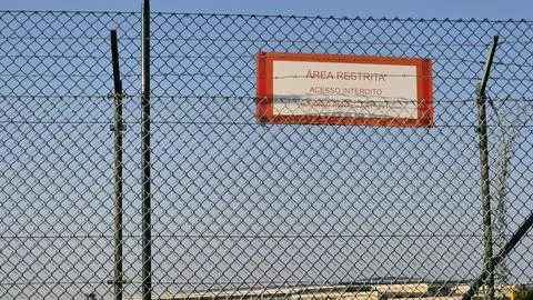 A security fence with barbed wire marks the perimeter of a restricted area Stock Photos
