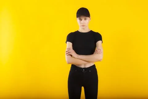 Security girl in black with accusing sight and folded hands copy space on yellow Stock Photos