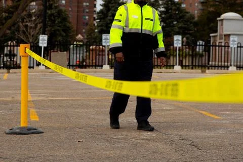 Security guard with caution tape to do parking enforcement at guest parking lot. Stock Photos