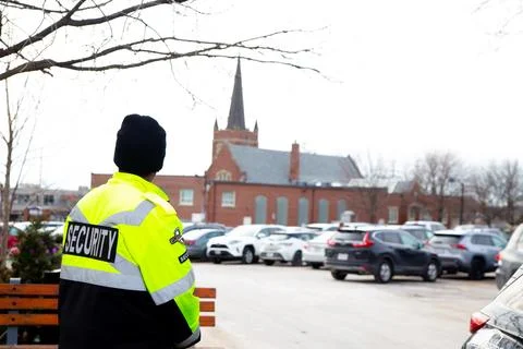 Security guard with caution tape to do parking enforcement at guest parking lot. 库存照片