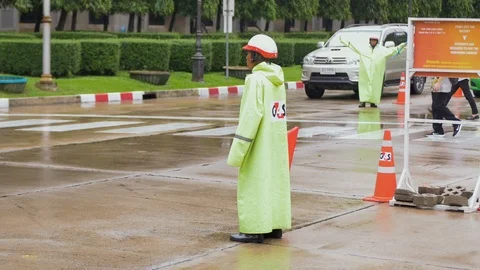 Security guard directing traffic at busy junction during rush hour on rainy day Video stock 112671832