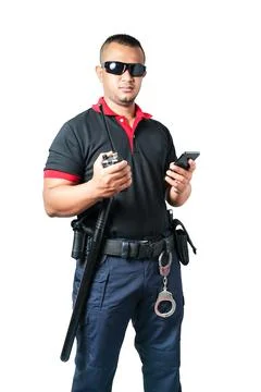 A security guard dressed in black, wearing black glasses, stands with a cell  Stock Photos