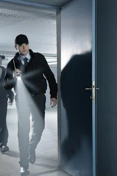 Security guard with flashlight entering empty parking garage Stock Photos