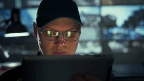 A security guard in glasses and protective gear scans a tablet monitor in a Stock Footage 334546079
