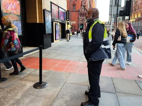 Security guard in high visibility jacket standing on a busy Manchester stre.. Stock Photos